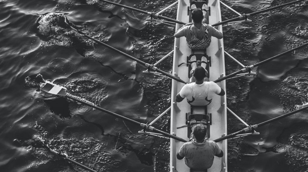 Team of men doing competitive rowing on water